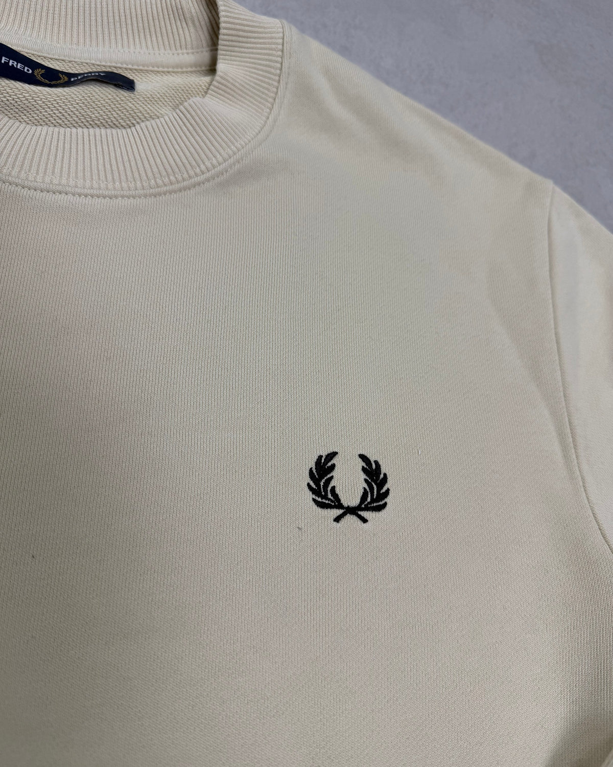 Fred Perry Pullover Creme mit schwarzem Lorbeerkranz – Detail