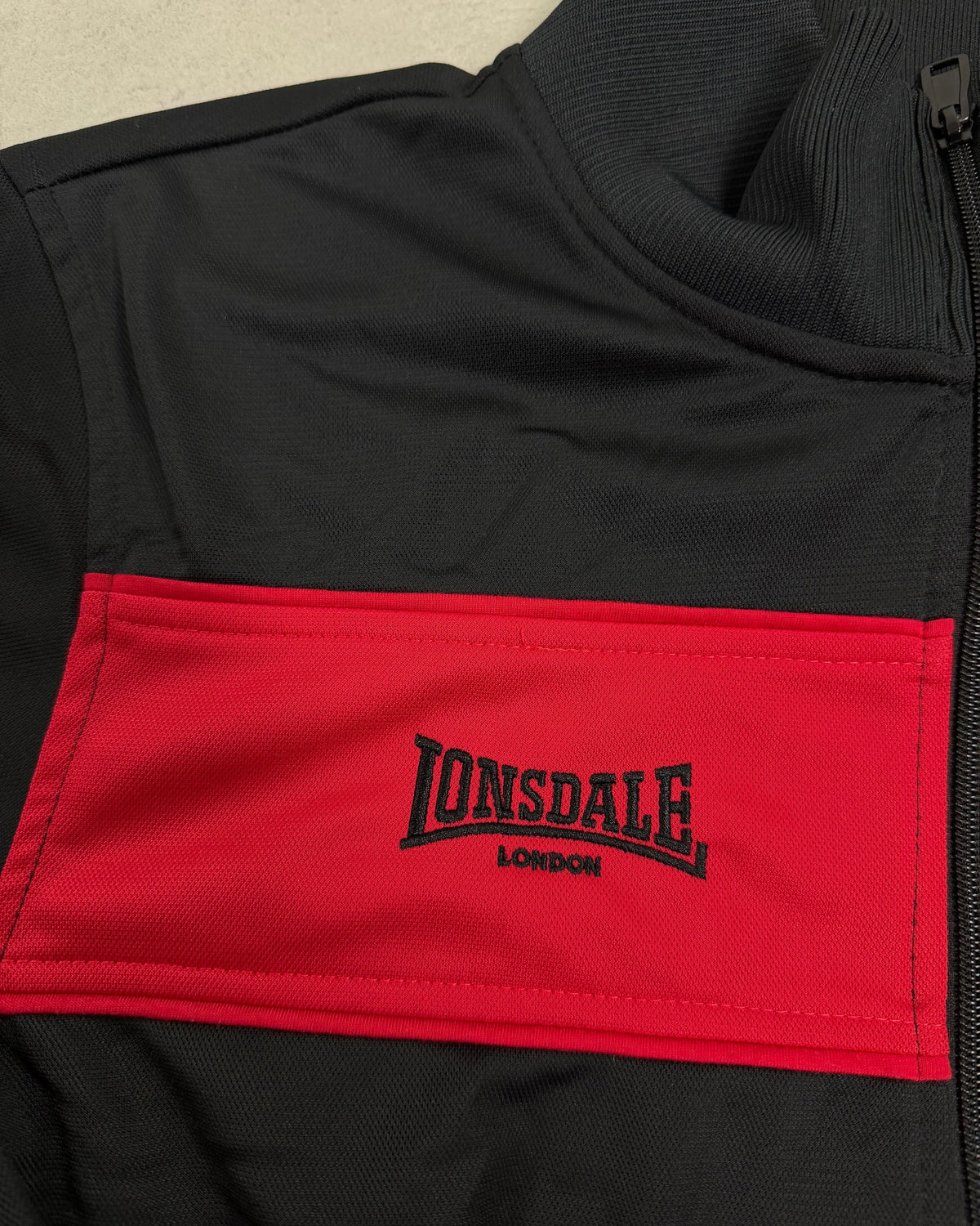 Lonsdale Trainingsjacke Schwarz mit rotem Brustblock Größe L – Detail